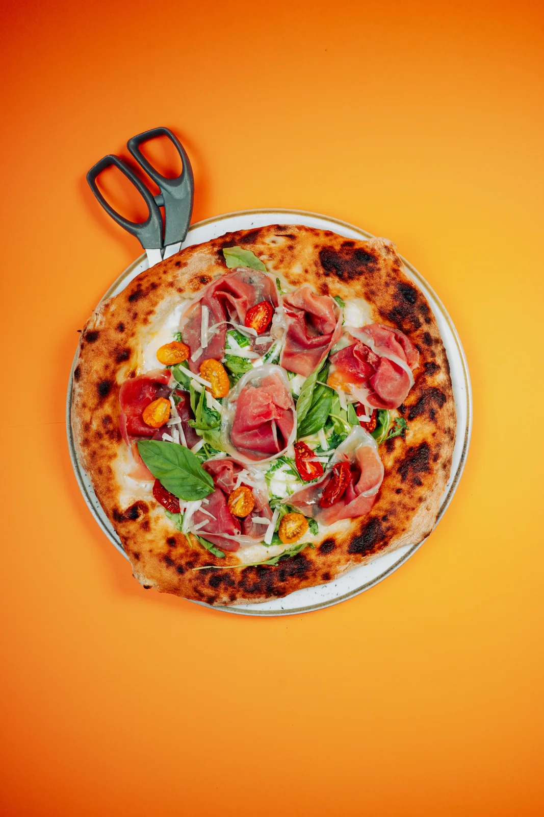 Pizza con salumi, formaggio e basilico vista dall’alto