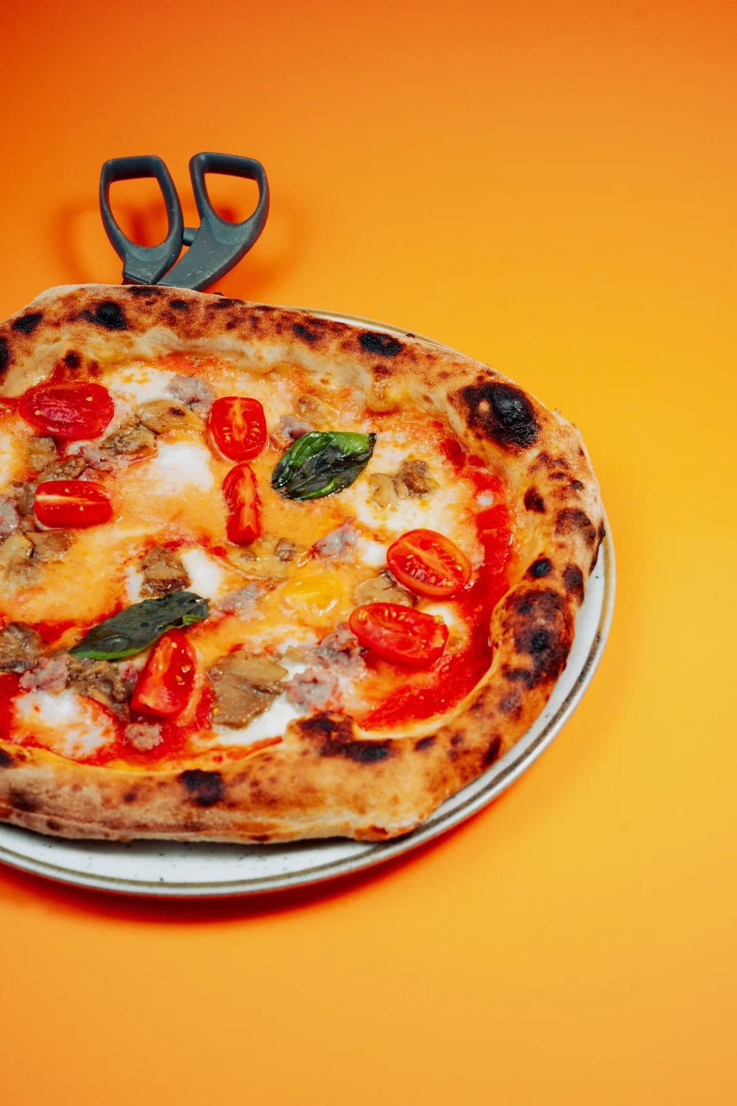 Pizza contemporanea con pomodorini e forbici per il taglio